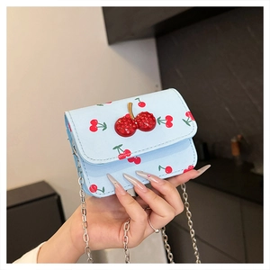 Détail du mini sac à rabat bleu clair avec imprimé cerise et ornement cerise en strass