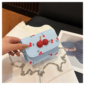 Gros plan du sac bandoulière bleu clair avec imprimé cerises et fermoir en strass