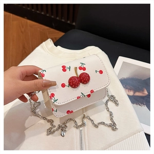 Détail du mini sac blanc avec imprimé cerise et fermoir cerise orné de strass brillants
