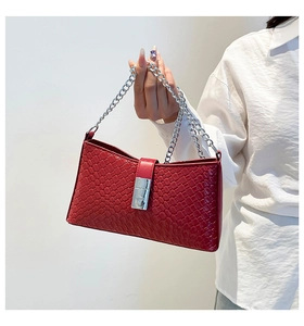 Detail of red woven texture underarm bag with thick silver chain strap and metal buckle