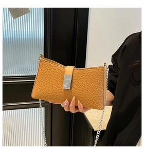 Detail of camel woven texture underarm bag featuring a silver rectangular metal clasp