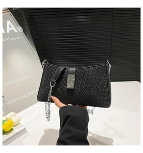 Détail d'un sac à main tressé noir avec un fermoir carré en métal argenté élégant