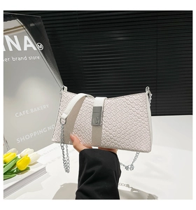 Détail de la texture tissée blanche du sac avec boucle argentée et bandoulière