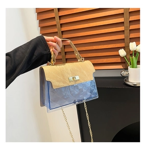 Detail of transparent blue PVC crossbody bag with diamond pattern and gold metal rotary clasp