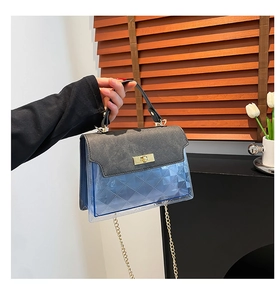 Detail of grey leather top and blue translucent PVC handbag with golden turn-lock