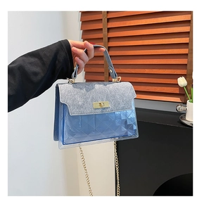 Detail of blue transparent bag with sequins, quilted pattern, and gold metal twist lock