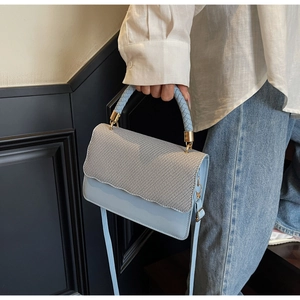 Detail of light blue leather bag with silver wavy flap and woven handle