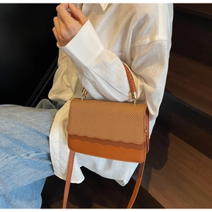 Detail of stylish woven pattern and brown contrast leather on women underarm bag