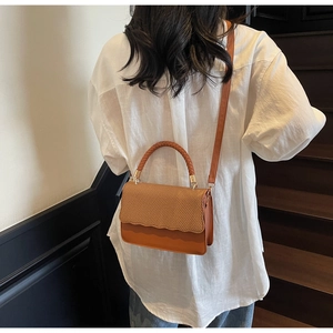 Detailed back view of a brown woven shoulder bag shown on a model for size reference