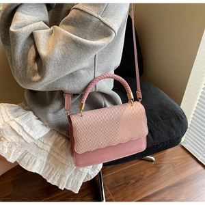 Détail du sac bandoulière rose avec rabat ondulé et texture tissée porté par le mannequin