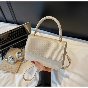 Close-up of cream crossbody shell bag with woven handle and elegant textured wave flap