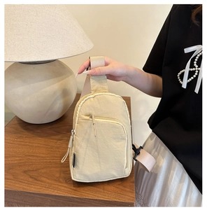 Détail d'un sac de poitrine en nylon beige avec fermetures éclair et boucle sur bois