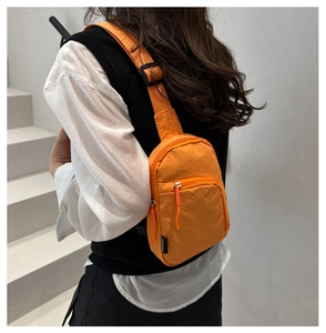 Détail d'un sac bandoulière orange vif en nylon imperméable avec sangle réglable