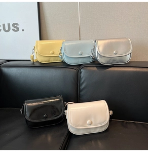 Detailed view of five mini flap crossbody bags in various colors on a black leather sofa