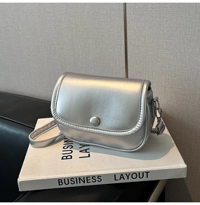 Macro detail of silver metallic textured crossbody bag with silver buckle and leather folds