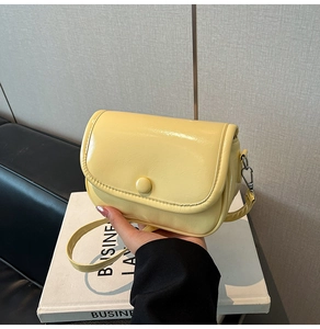 Detailed shot of yellow glossy mini square crossbody bag with snap closure