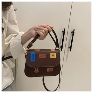 Détail du sac besace en cuir marron foncé avec écussons brodés LOVE et cœur colorés