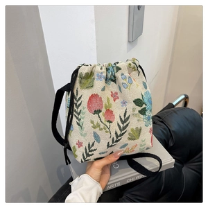 Detail of floral jacquard bucket bag featuring drawstring closure and woven strap