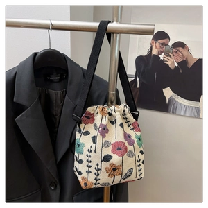 Close-up of floral print drawstring bucket bag with black canvas strap on a display rack
