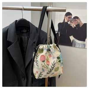 Detail of floral jacquard bucket bag with black drawstring closure and shoulder strap