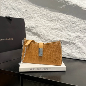 Yellow woven texture shoulder bag with silver buckle and chain strap on marble display