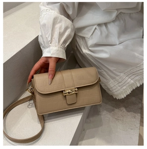 Detail of beige crocodile embossed crossbody bag with golden bamboo twist lock closure