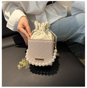 Detailaufnahme von Perlengriff und Goldkette an einer beigen geometrischen Tunnelzug-Tasche