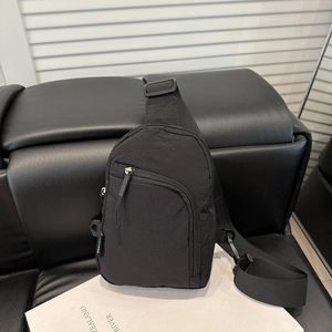 Sac de poitrine minimaliste en nylon noir avec sangle réglable sur un canapé en cuir