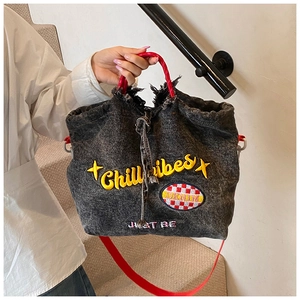 Detail of washed black denim tote with Chill Vibes embroidery and red fringe handles