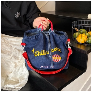 Detail of blue denim tote bag with red strap and Chill Vibes embroidery texture