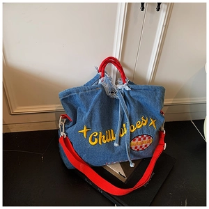 Detail of blue denim tote bag with red handles and yellow Chill vibes embroidery