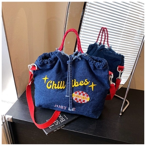 Detail of blue denim tote bag with red handles and yellow Chill Vibes embroidery