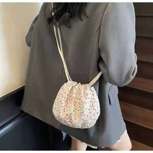 Detail of floral canvas bucket bag with drawstring closure worn by model on stairs