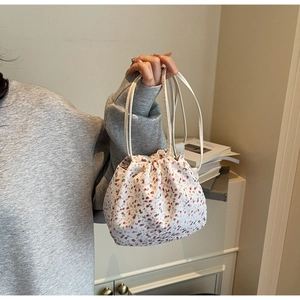 Détail du sac en toile fleurie avec cordon, montrant le motif délicat et la texture