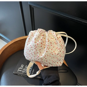 Détail du sac cabas floral en toile avec fermeture à cordon et fine bandoulière crème