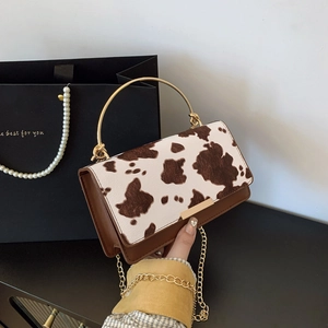 Chic cow print crossbody bag with gold round metal handle and slim chain strap