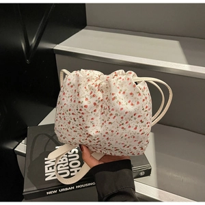 Détail du sac à cordon avec motif floral rouge et fine bandoulière blanche