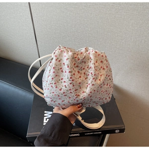 Gros plan du sac seau à cordon fleuri avec motifs de fleurs rouges et bandoulière blanche