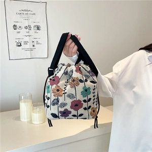Floral knit drawstring bucket bag with colorful woven patterns and black wide strap