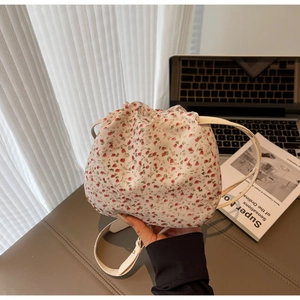 Détail d'un sac seau en toile fleurie avec cordon et bandoulière en cuir