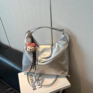 Macro detail of silver metallic hobo bag with Capnes logo and plush bear charm