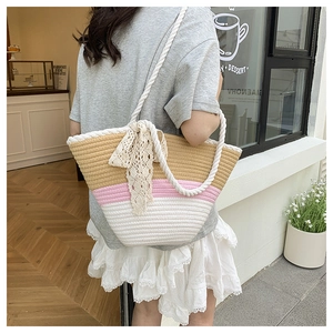 Detailed texture of tricolor woven straw tote bag with cotton rope handles and lace bow