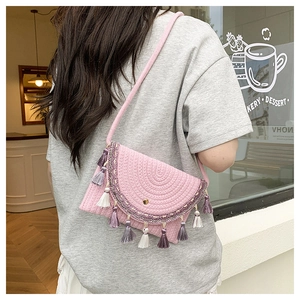 Detail of pink hand-woven straw bag with colorful tassels and ethnic floral embroidery