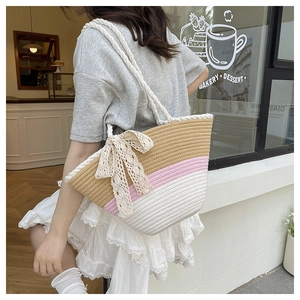 Detail of woven tote bag featuring tricolor stripes and a large lace bow decoration