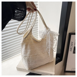Detail of white lace tote bag with delicate crochet flowers and large side bow