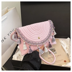 Detail of pink woven saddle bag featuring colorful tassels and ethnic embroidery accents