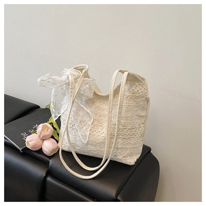 Close-up of cream lace tote bag with bow detail on a leather seat with tulips