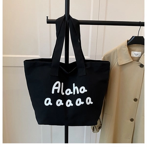 Close-up of black canvas tote bag with artistic Alaha letter printing and wide shoulder strap