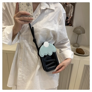 Detail of cute cherry cake style crossbody phone bag with light blue wavy edges and black strap