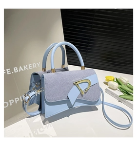 Detail of light blue denim and leather bag with gold D-buckle and elegant twin handles